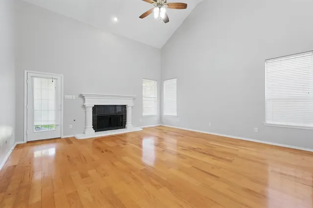 an empty room with chandelier fan and windows