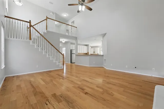 a view of an empty room with a chandelier fan and kitchen view