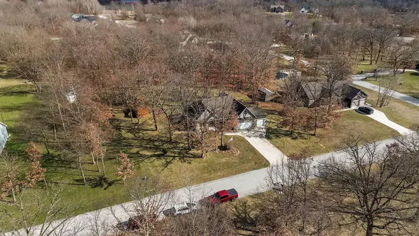 a aerial view of a house with a yard and large trees