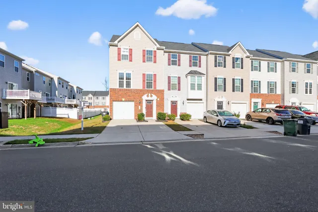 a view of multiple houses with cars parked on the road