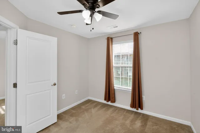 an empty room with a ceiling fan and a window