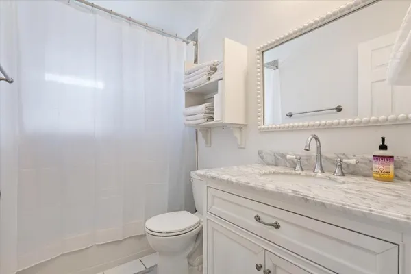 a bathroom with a granite countertop toilet sink mirror and cabinets
