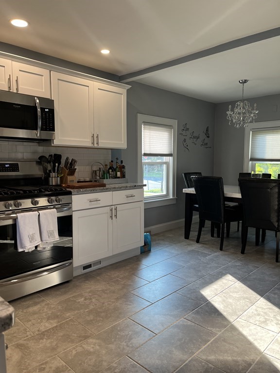 239 Plumtree Road Springfield, MA 01118 - Photo 6 of 14 a kitchen with stainless steel appliances kitchen island granite countertop a sink a stove a microwave a dining table and chairs