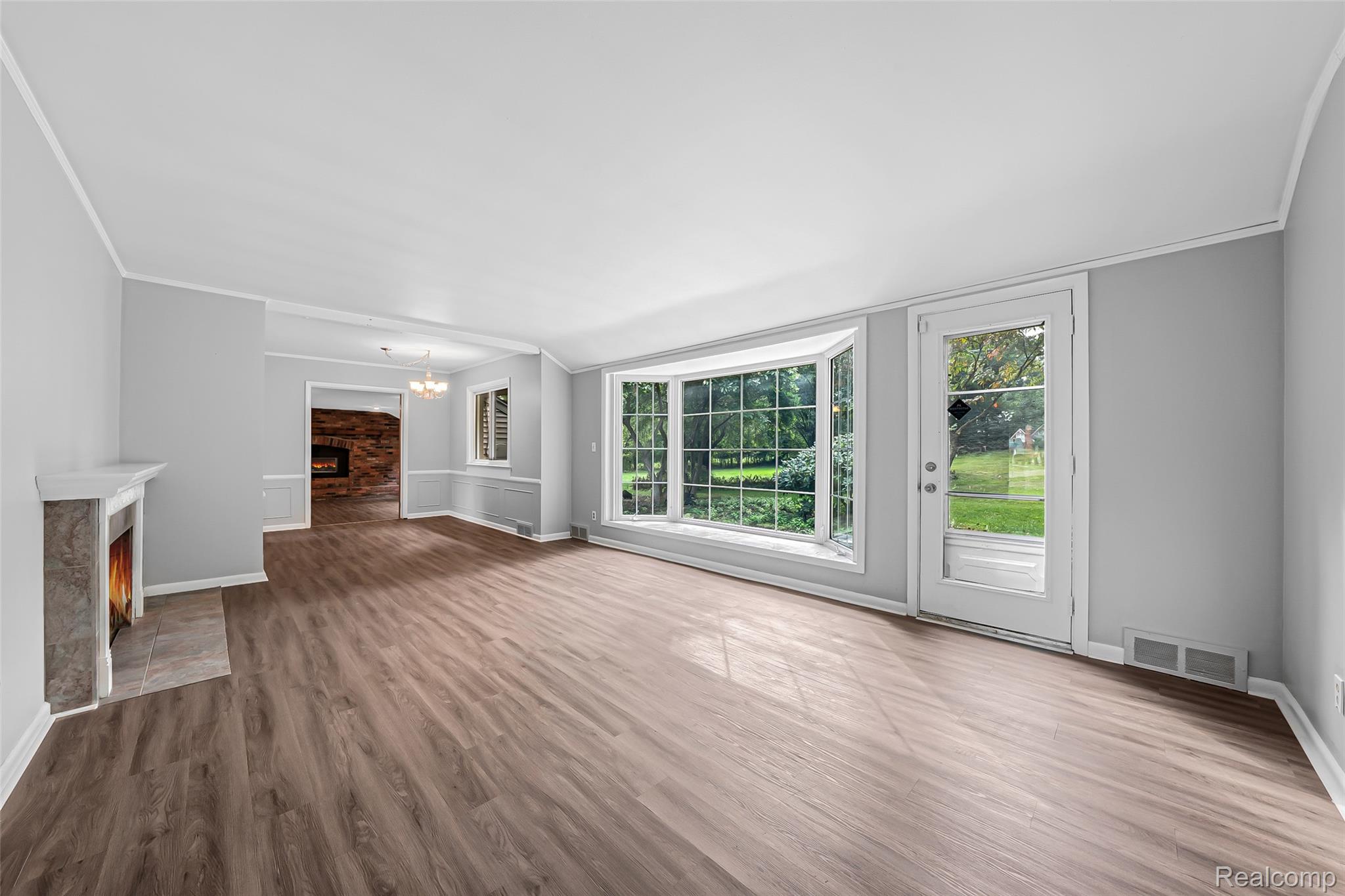 2329 Rutherford Road Bloomfield Hills, MI 48302 - Photo 19 of 46 Light gray walls, wood-finish flooring, a decorative fireplace with a stone surround, a bay window, and a glass-paneled exterior door