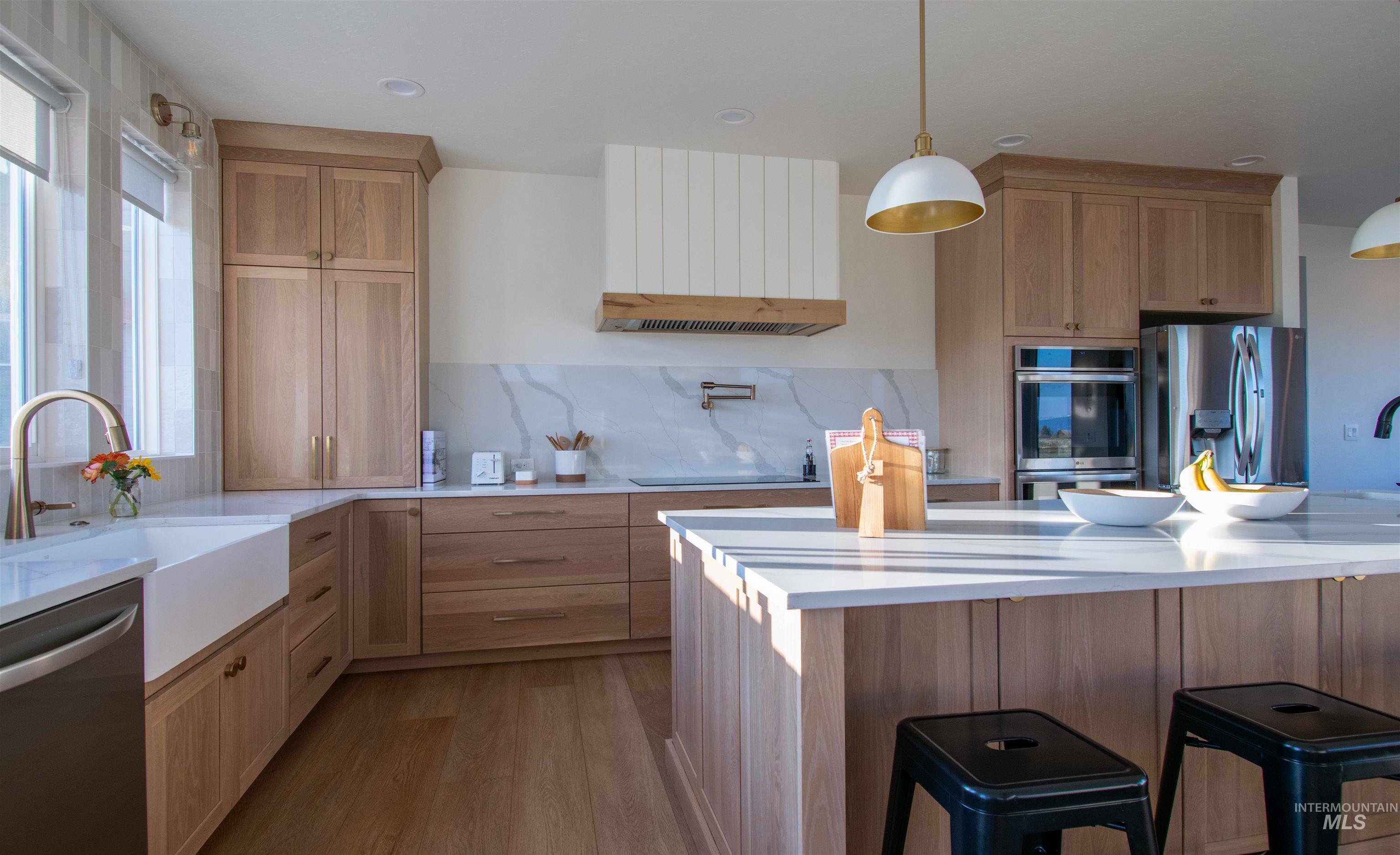 44 Big Moose Road McCall, ID 83638 - Photo 8 of 50 Gourmet kitchen featuring a large central island, white apron-front sink, light wood-finish cabinetry, stainless steel appliances, and a marble-finish backsplash