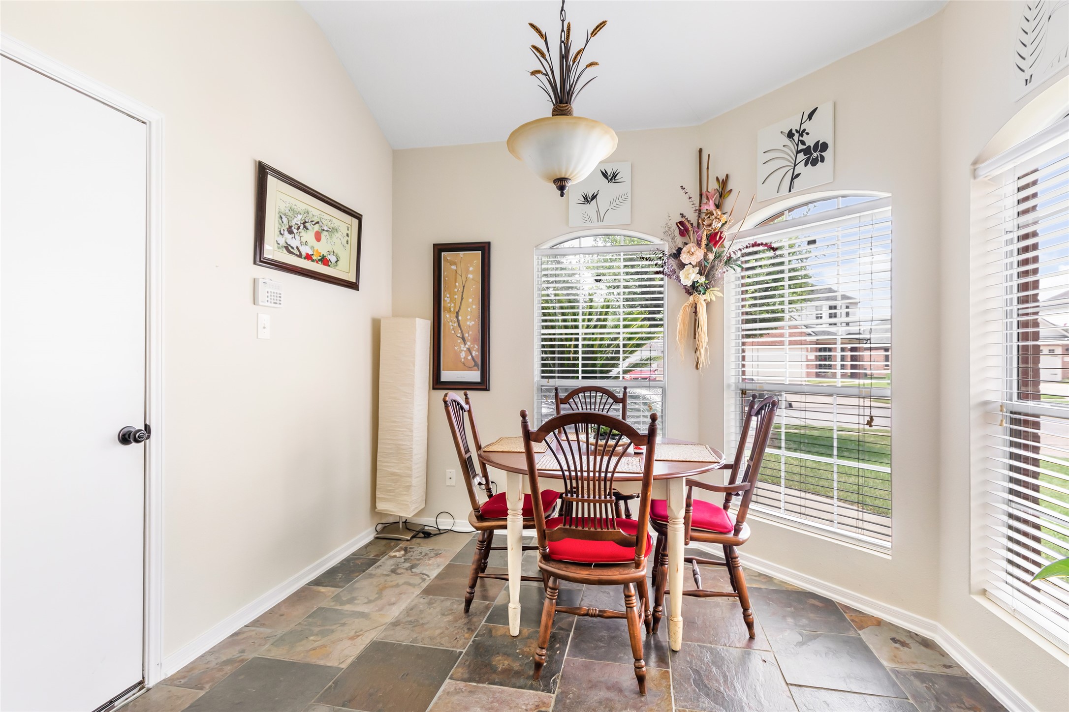 12122 Landsdown Ridge Way Humble, TX 77346 - Photo 16 of 34 This photo shows a bright dining area with large windows, slate tile flooring. The space features a stylish light fixture, making it an inviting spot for meals with a view of the outside.