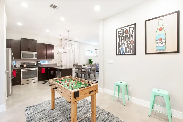 a kitchen with stainless steel appliances kitchen island granite countertop a refrigerator and a stove top oven with wooden floor