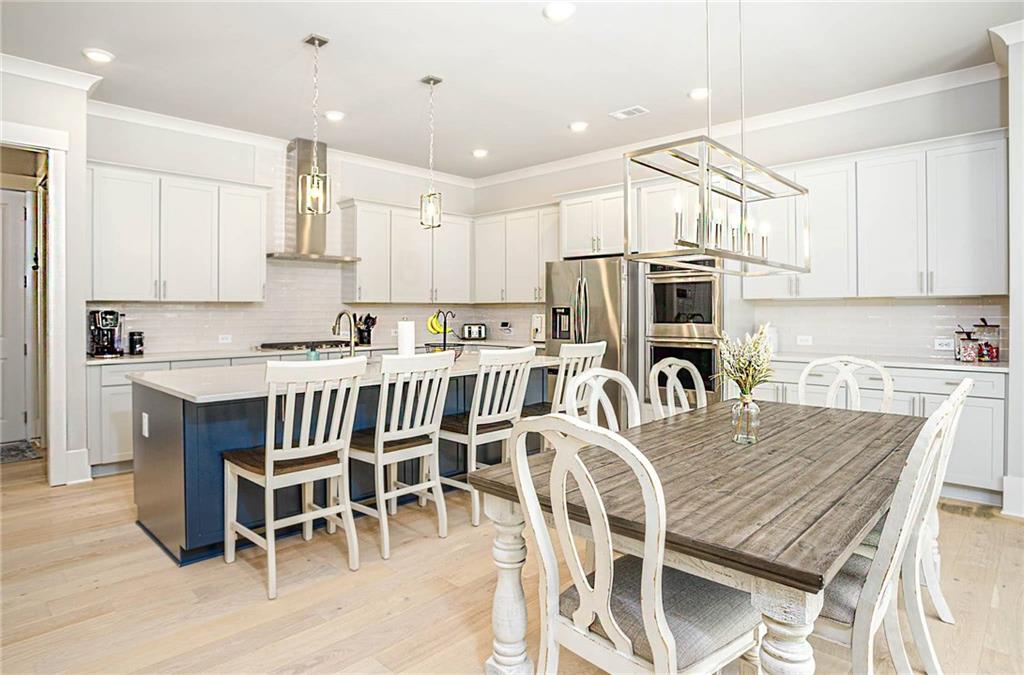 255 Old Town Road Dacula, GA 30019 - Photo 12 of 35 a kitchen with stainless steel appliances granite countertop a table chairs a sink a stove a microwave a refrigerator and cabinets