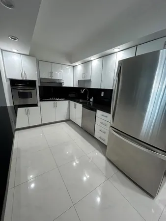 a view of a refrigerator in kitchen and an empty room