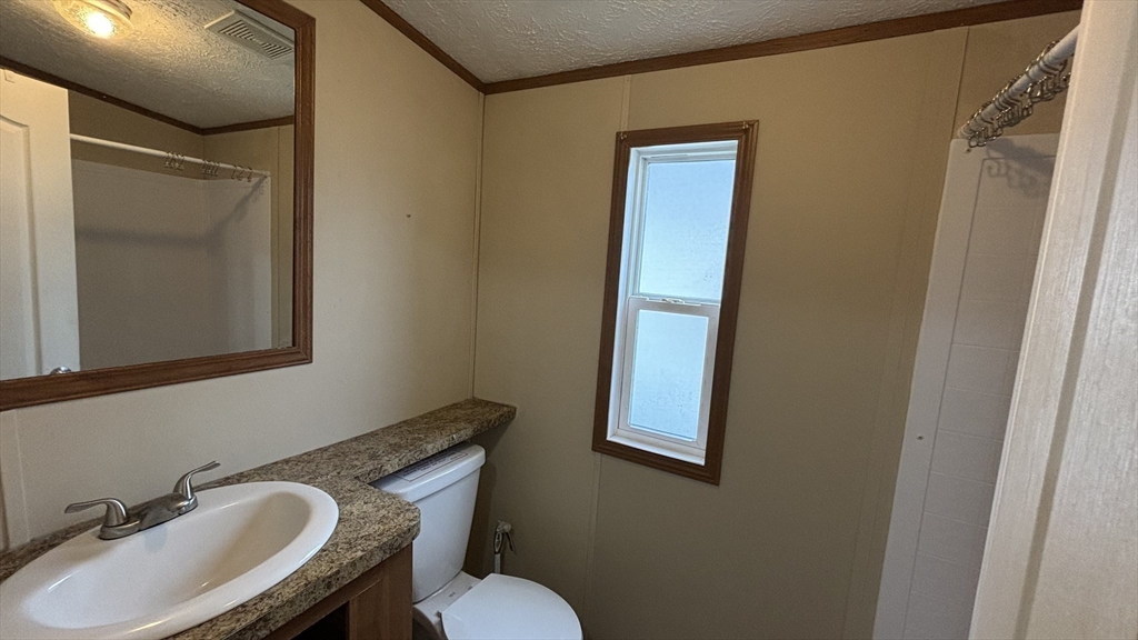 557 Southwest Cutoff, Unit 47 Worcester, MA 01607 - Photo 8 of 10 a bathroom with a granite countertop sink toilet and mirror