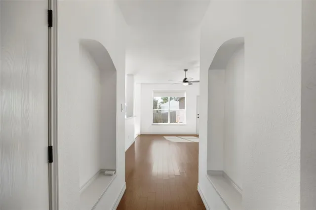 a view of a hallway with wooden floor and a bathroom