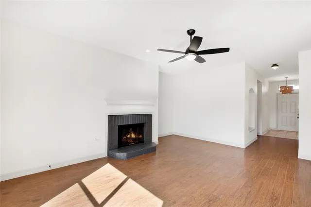 a view of an empty room with wooden floor and a fireplace