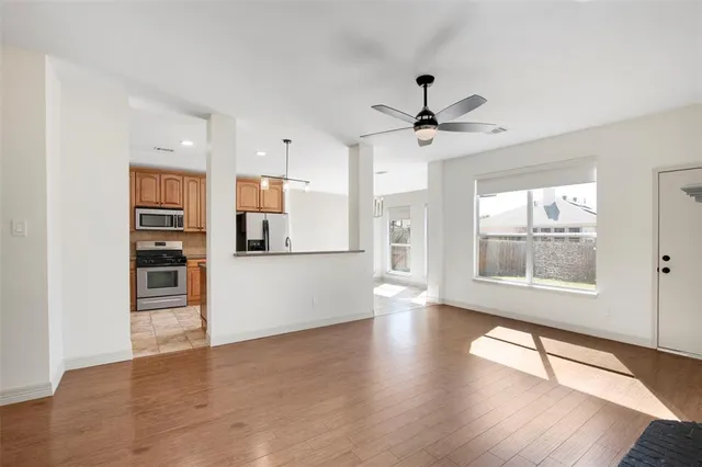 a view of an empty room with a kitchen and wooden floor