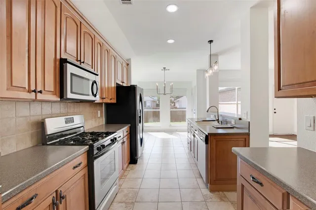 a kitchen with stainless steel appliances granite countertop a stove a sink and a refrigerator