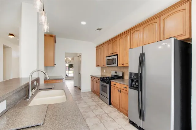 a kitchen with granite countertop a refrigerator stove top oven and sink