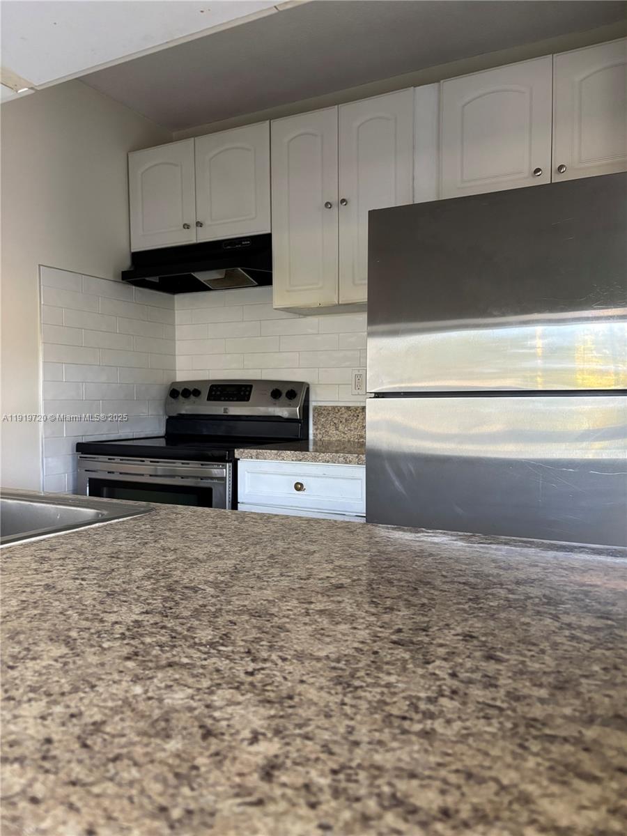 6031 10th Avenue North, Unit 218 Greenacres, FL 33463 - Photo 4 of 9 a kitchen with granite countertop a stove a sink and a white cabinets