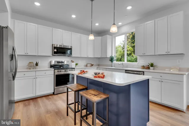 a kitchen with kitchen island granite countertop a sink a counter space appliances and cabinets
