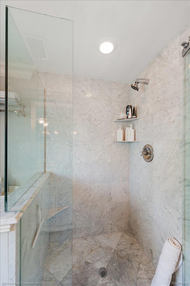 135 Clifton Road Bloomfield Hills, MI 48301 - Photo 56 of 77 Shower enclosure featuring floor-to-ceiling glass, full stone tile walls, a stone tile floor, and built-in shelving