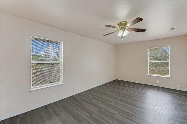 a view of an empty room with a window and wooden floor