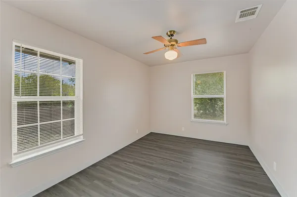 a view of an empty room with a window and wooden floor