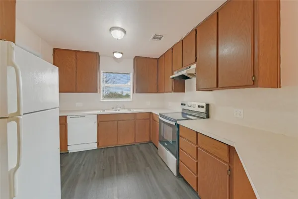 a kitchen with a sink a refrigerator and wooden cabinets