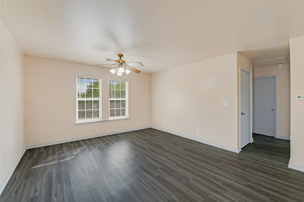 a view of an empty room with wooden floor and a window