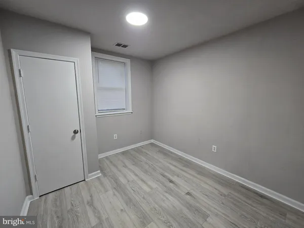 an empty room with wooden floor and mirror