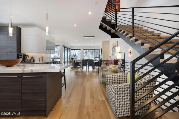 a open kitchen with stainless steel appliances kitchen island granite countertop a stove a sink a dining table and chairs with wooden floor
