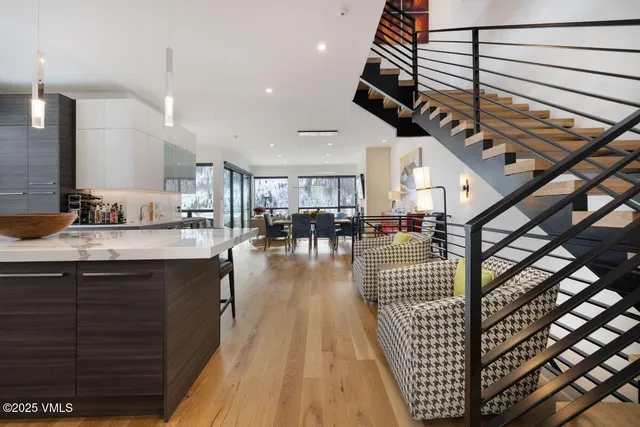 a open kitchen with stainless steel appliances kitchen island granite countertop a stove a sink a dining table and chairs with wooden floor