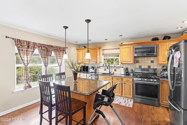 a kitchen with stainless steel appliances granite countertop a stove top oven a sink with a dining table and chairs
