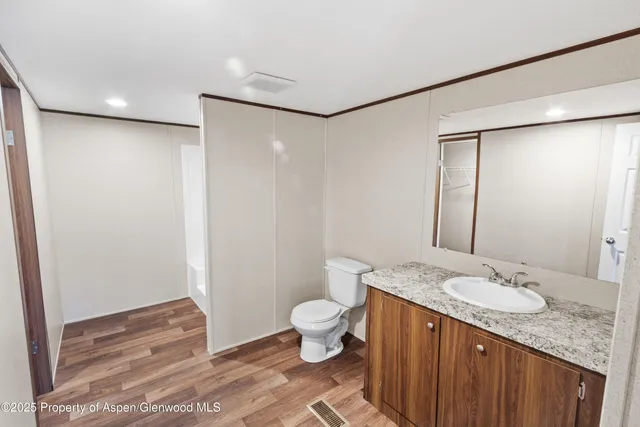 a bathroom with a granite countertop sink a toilet and shower
