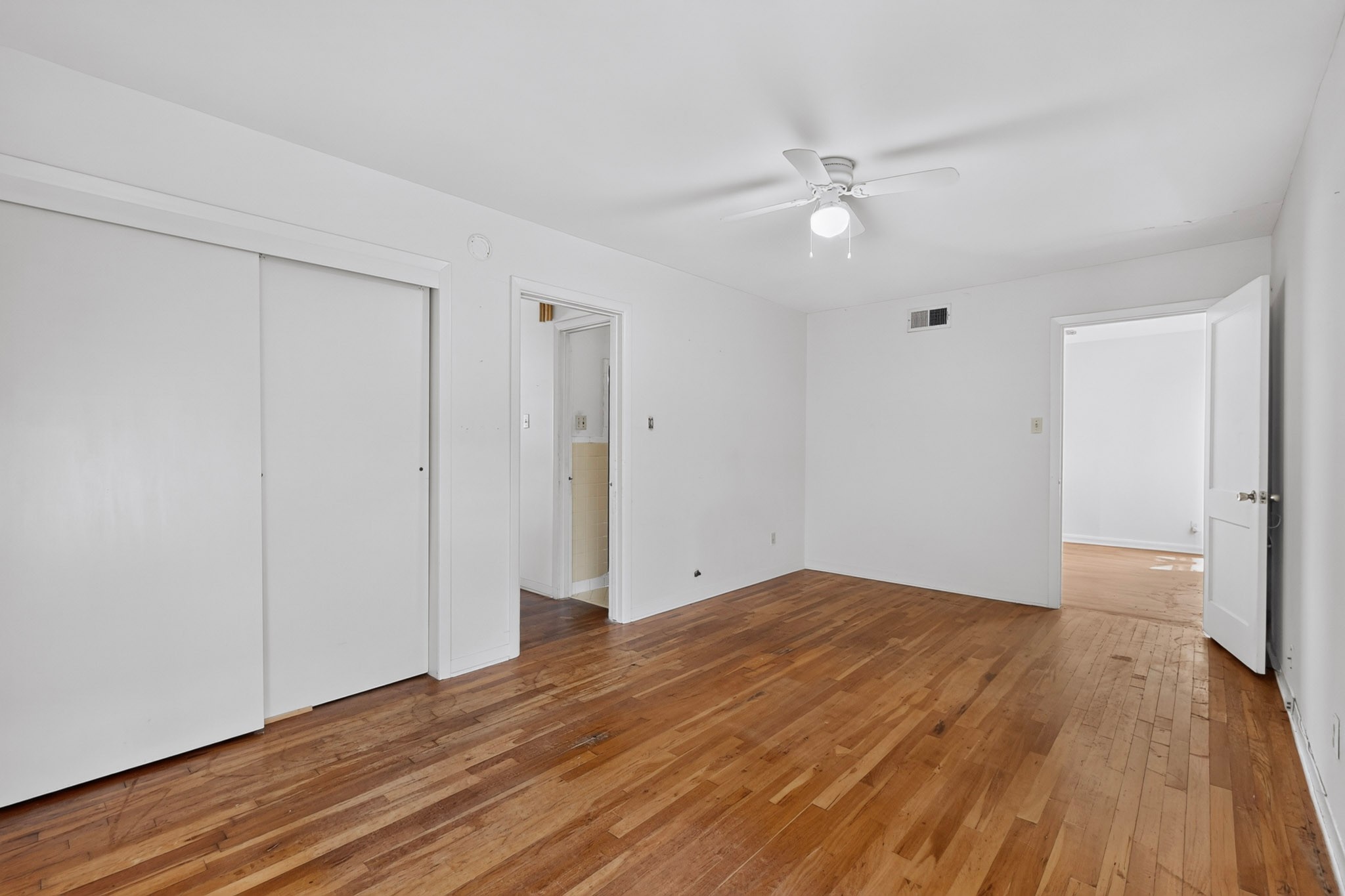 4703 Leslie Avenue Austin, TX 78721 - Photo 21 of 34 Hardwood floors stretch across this spacious room, complemented by a ceiling fan for comfort.
