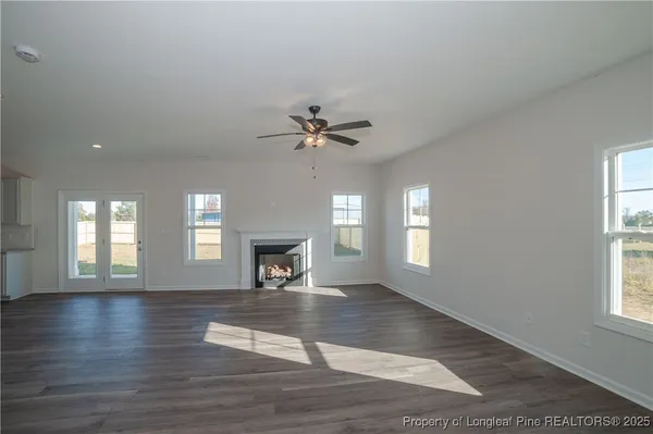 an empty room with wooden floor a fireplace and windows