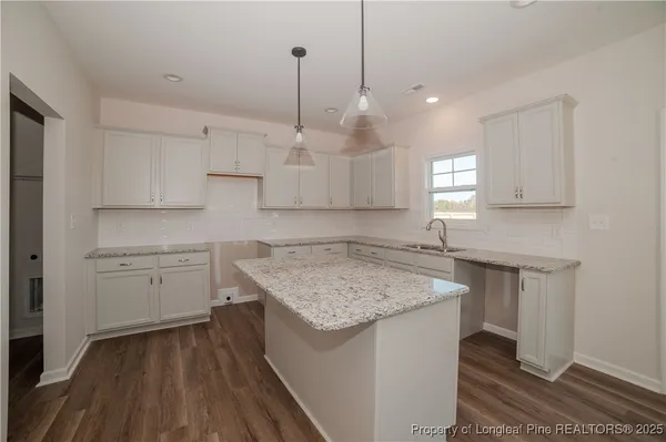 a kitchen with kitchen island white cabinets stainless steel appliances a sink and a stove