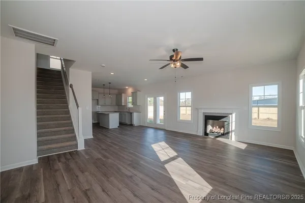 a view of an empty room with wooden floor and a fireplace