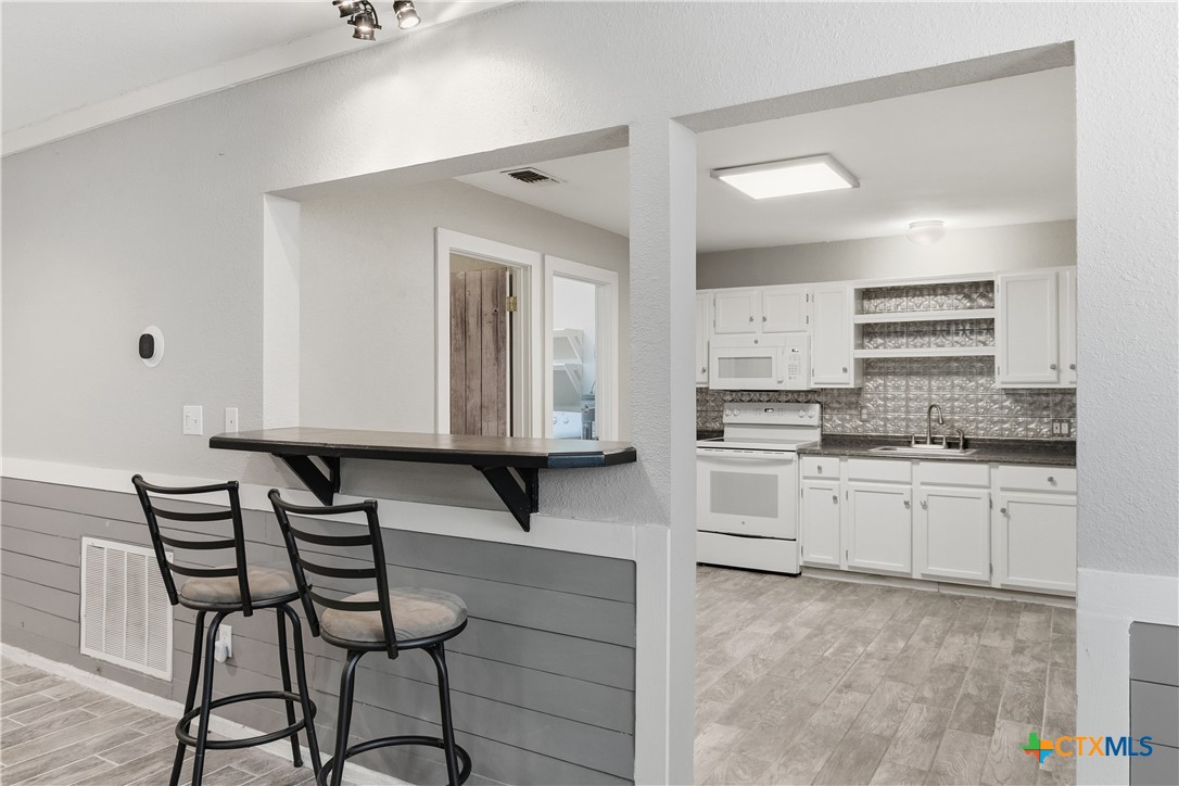 332 West Klein Street Seguin, TX 78155 - Photo 8 of 24 a kitchen with granite countertop white cabinets and white appliances