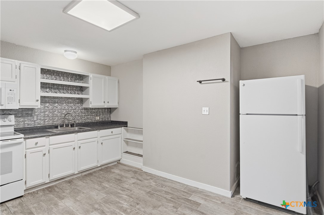 332 West Klein Street Seguin, TX 78155 - Photo 10 of 24 a kitchen with a sink a refrigerator and cabinets