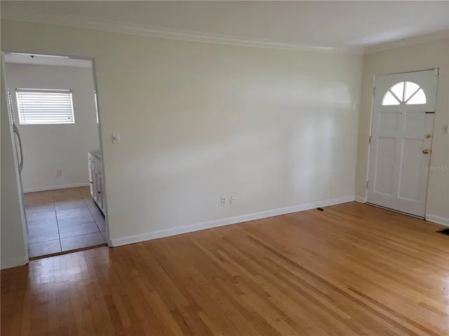 an empty room with wooden floor and mirror