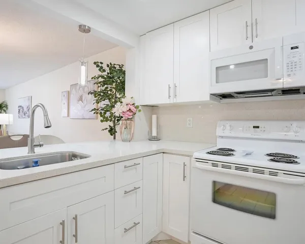 a kitchen with white cabinets and white appliances