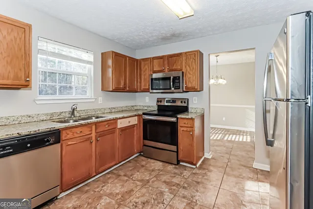 a kitchen with stainless steel appliances granite countertop a stove a sink and a refrigerator
