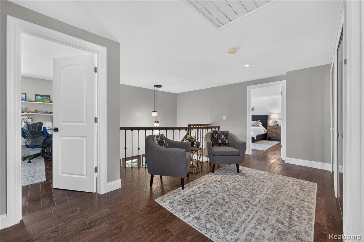7330 West Gates Street Romeo, MI 48065 - Photo 27 of 73 Hardwood-finish flooring throughout, featuring a white paneled door, black metal balusters, and a contemporary pendant light fixture
