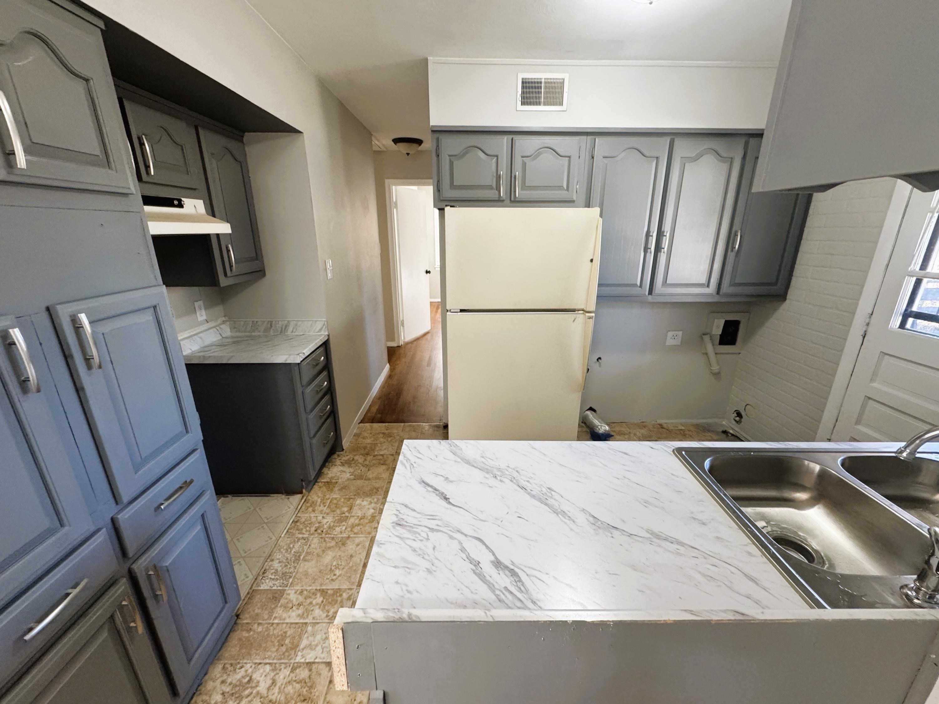 4956 Owen Road Memphis, TN 38122 - Photo 6 of 14 Kitchen featuring freestanding refrigerator, gray cabinetry, light countertops, range hood, and light floors