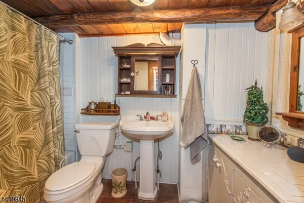 a bathroom with a sink a mirror a toilet and a window