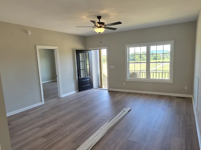 a view of an empty room with wooden floor and a window
