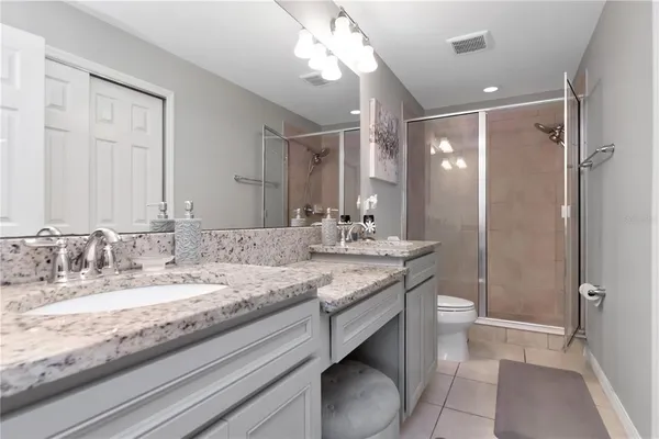 a bathroom with a granite countertop sink a toilet and a mirror