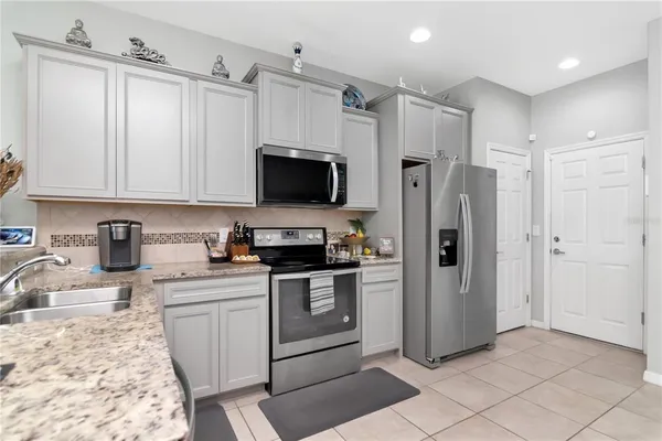 a kitchen with stainless steel appliances granite countertop a refrigerator sink and white cabinets