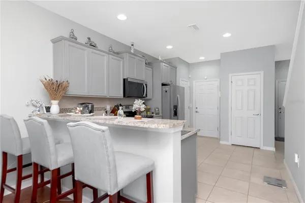 a living room with stainless steel appliances a table chairs refrigerator and microwave