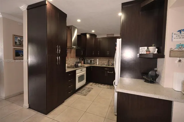 a kitchen with stainless steel appliances kitchen island granite countertop a refrigerator and a sink