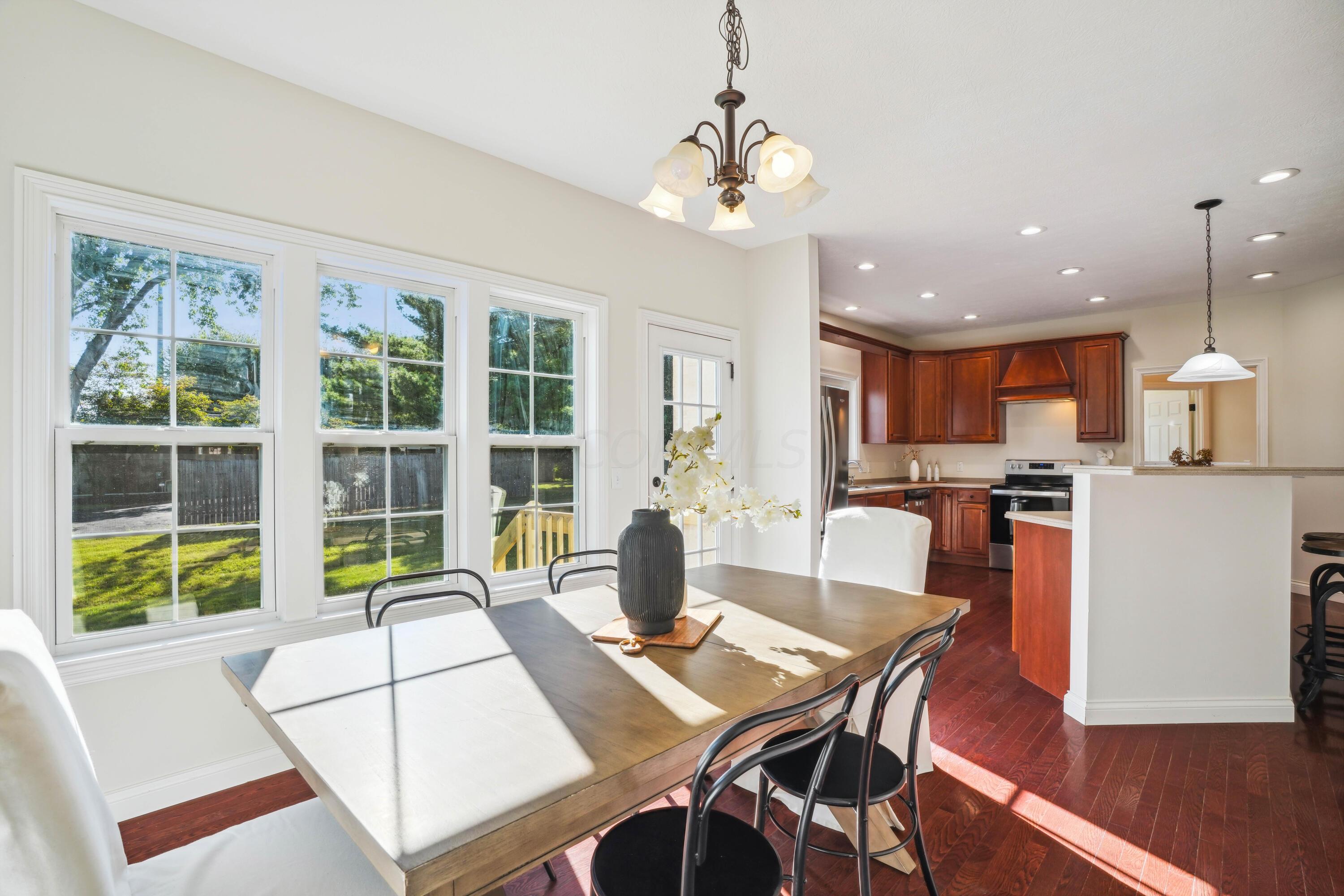 10403 Liberty Road Powell, OH 43065 - Photo 24 of 76 Open Kitchen with countertop seating, NEW SS appliances, Dining Area, Cherry cabinets with custom vent hood, corian countertops and walk-in pantry plus beautiful hardwood floors!
