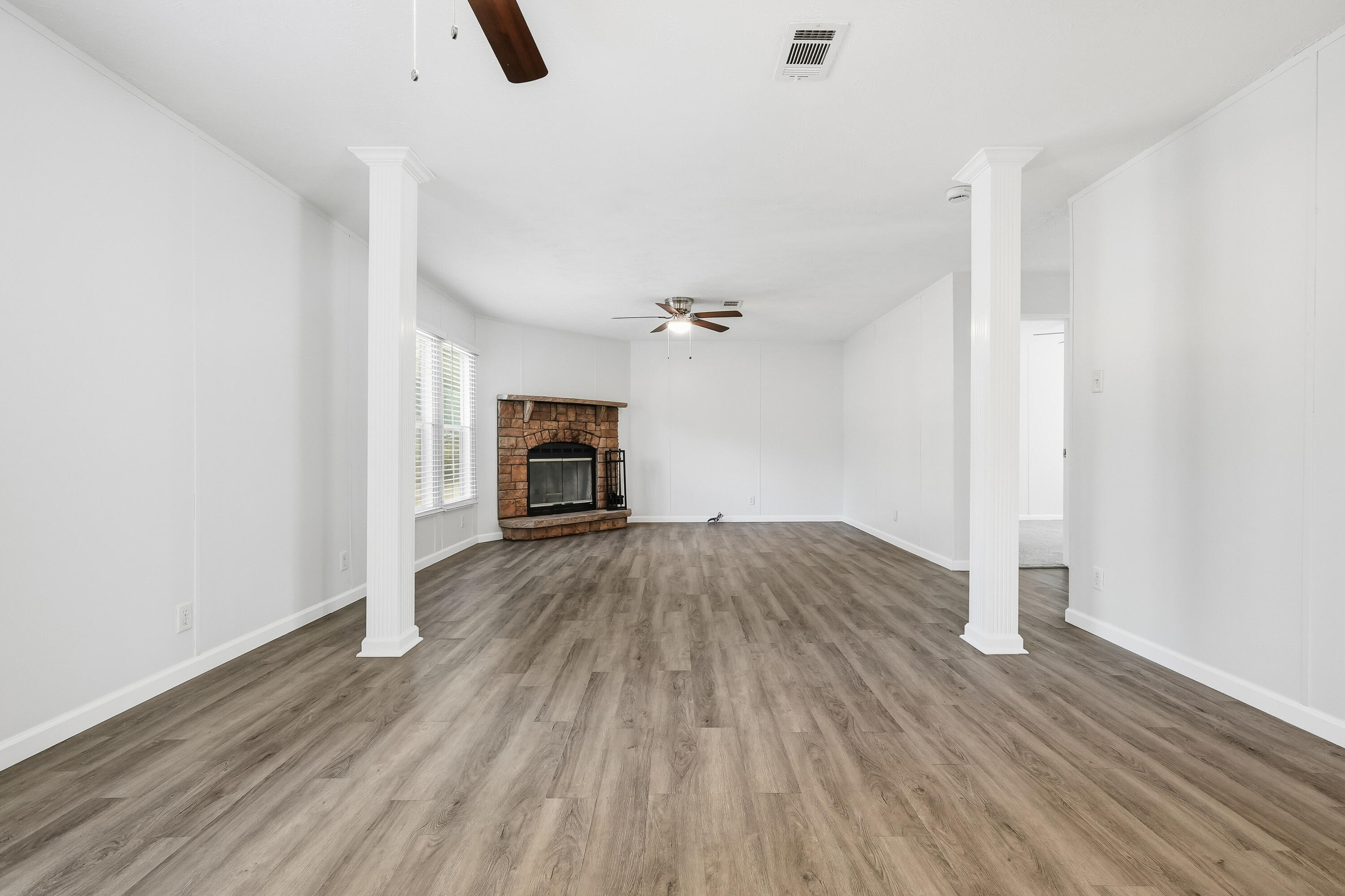 482 Roberts Road East DeFuniak Springs, FL 32433 - Photo 22 of 61 an empty room with wooden floor fireplace and windows